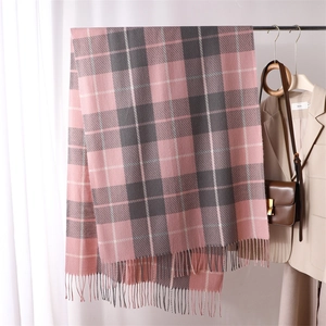 Detail of pink and grey plaid scarf with soft tassels hanging in a stylish cozy room