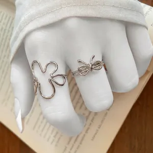 Ensemble de bagues argentées avec nœud et fleur en résine portées sur un livre
