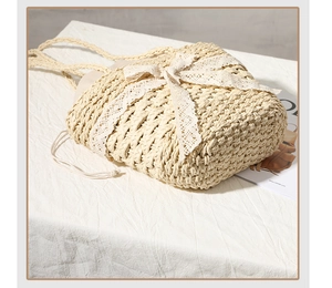 Close-up of straw woven shoulder bag with delicate white lace bow and drawstring lining