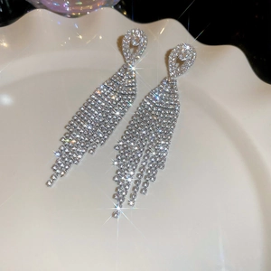 Detail view of sparkling silver drop tassel earrings with rhinestones on a white plate