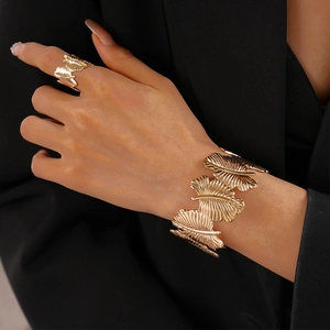 Detailed view of textured gold leaf rings and wide leaf bracelet on model in black suit