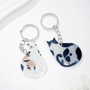 Detail of calico and tuxedo cat acrylic keychains with silver metal rings and chains