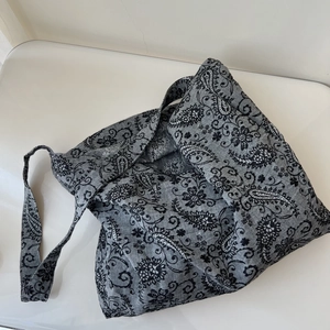 Detail view of ethnic paisley linen bag with wide shoulder strap in grey tones