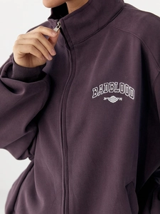 Detail of dark purple zip-up sweatshirt with 1991 embroidery and stand collar texture