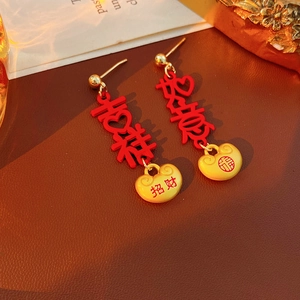 Macro detail of vintage Chinese lucky lock earrings with red enamel and gold tassels