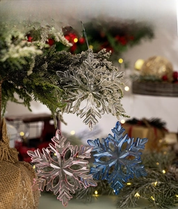 Close-up of clear acrylic snowflake ornaments hanging on a festive Christmas tree