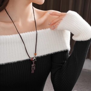 Close-up of a brown abstract figure pendant necklace with tassels on a model