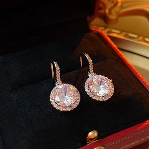 Macro shot of silver circular zircon earrings with halo micro-pave setting on black velvet