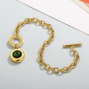 Detailed top view of gold OT buckle bracelet with a green faceted gemstone charm