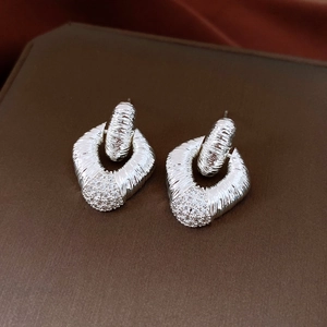 Detail of silver diamond-set earrings with diamond texture on a brown leather surface
