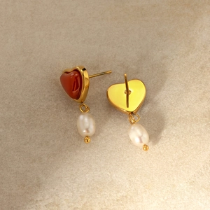 Detail of 18k gold heart earring with red agate stone and white baroque pearl drop