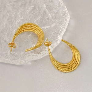Minimalist gold textured twisted geometric earrings on an ice-textured decorative block
