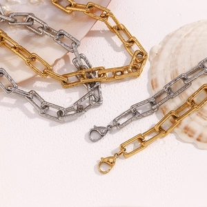 Close-up of gold and silver textured lava square link necklaces on a seashell background