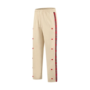 Detail of beige casual pants featuring red-green plaid side stripes and red buttons