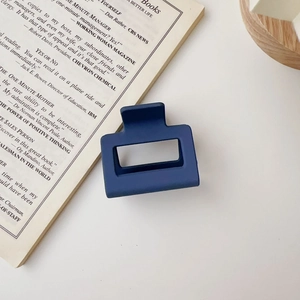 Detail of a blue matte geometric hair claw clip with a stylish hollow rectangle design
