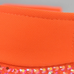 Dettaglio della visiera arancione in mesh traspirante con strass rosa brillanti