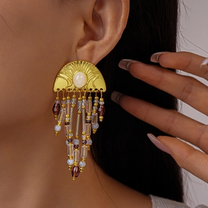 Detail of gold semicircular earrings with white stones and colorful beaded tassels