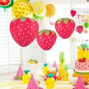 Hanging strawberry-shaped paper lanterns with white dots for festive party decorations
