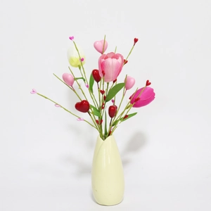 Detailed view of pink tulips and heart decorations in a round ceramic yellow vase