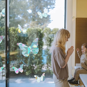 Mother and child by window with rainbow butterfly suncatcher stickers creating light effects