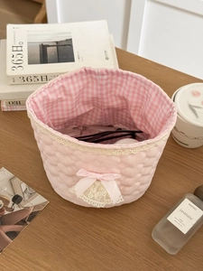 Detailed view of pink quilted lace basket with bow and checkered lining for desktop storage