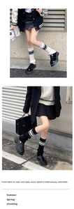 Close-up of knit leg warmers with three-stripe pattern in black and white styles