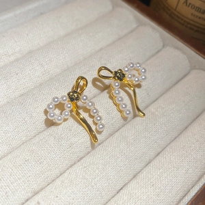 Detailed macro of 18k gold plated bow earrings with white pearls in a jewelry box