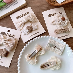 Vintage Beige Spitzen-Haarspangen mit Schleife und Strickblumen auf einem Holztisch