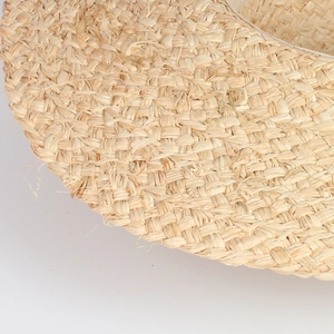 Macro detail of natural raffia weave on beige sun hat showing handwoven texture