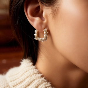 Détail d'une boucle d'oreille en U plaquée or 18 carats avec perle et cristaux sur modèle