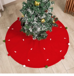 Détail du tapis de sapin de Noël rouge avec broderie d'arbre et pompons colorés