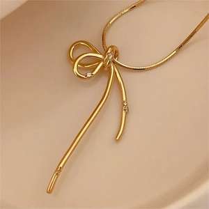 Macro detail of gold bow pendant with sparkling zircon inlay on smooth snake chain
