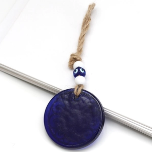 Detailed macro view of the blue glass evil eye pendant with braided hemp rope and beads