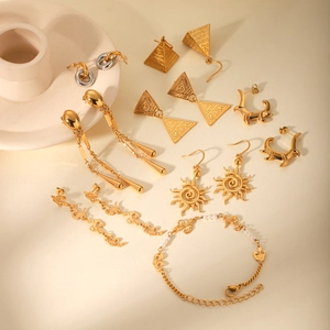 Detail showing gold geometric earrings with sunburst patterns and pearl bracelet accents