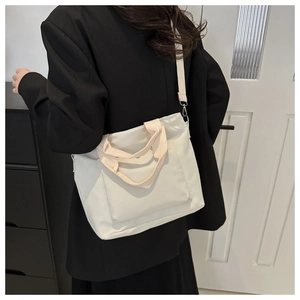 Detalle del bolso tote beige minimalista que muestra la textura de lona y la bandolera