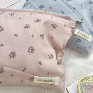 Detailed close-up of floral makeup bags with gold embroidered labels and rose patterns