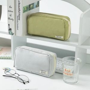 Detail of high-capacity olive green and light grey canvas pencil bags on a desktop