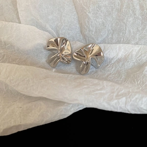 Macro detail of irregular pleated silver flower earrings with polished mirror finish