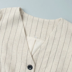 Close-up of oatmeal striped vest showing natural linen texture and black resin buttons