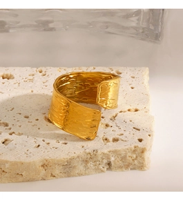 Detail shot of a wide gold cuff bracelet featuring a textured hand-hammered finish