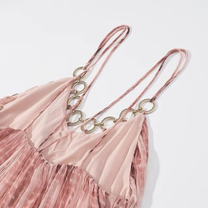 Dettaglio dell'abito plissettato tie-dye rosa con spalline sottili e anelli in metallo oro