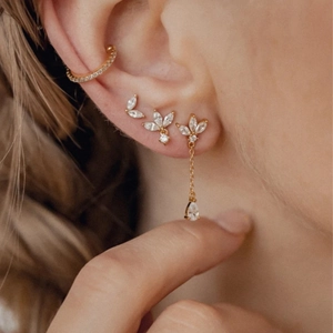 Close-up of gold ear cuff and leaf studs with sparkling zircons and a drop chain