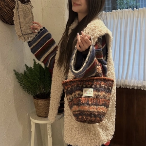 Detail of multi-colored knitted tote bag featuring a white square label and woven texture