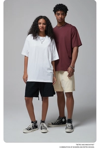 Detailed view of oversized cotton t-shirts and casual shorts on models in neutral grey studio