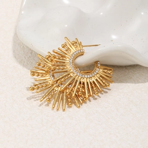 Detailed view of sunburst gold earring with crystals on elegant white ceramic display