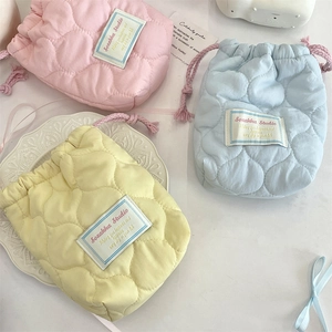 Close-up of quilted drawstring storage bags in pink, blue, and yellow fabric texture
