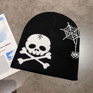 Detailed flat lay of black knit beanie with white skull and spider web patterns