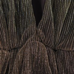 Elegant deep V-neck sleeveless black dress with shimmering gold stripes and pleated detail