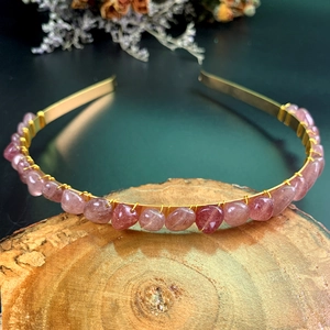 Detail of handcrafted gold crown headband with strawberry quartz stones on wood