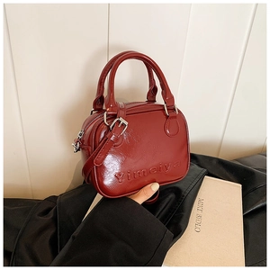 Detail of wine red faux leather handbag with embossed texture and metal hardware